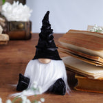 Load image into Gallery viewer, Gnome figurine with a black hat on a wooden surface with books and flowers.
