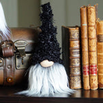 Load image into Gallery viewer, fall Gnome with black hat and frosty grey and white beard next to vintage books and a suitcase.
