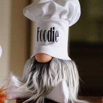 Load image into Gallery viewer, A handmade guardian, Chef Gnocchi gnome figurine with a foodie chef hat, long white beard, and round nose sits on a surface.
