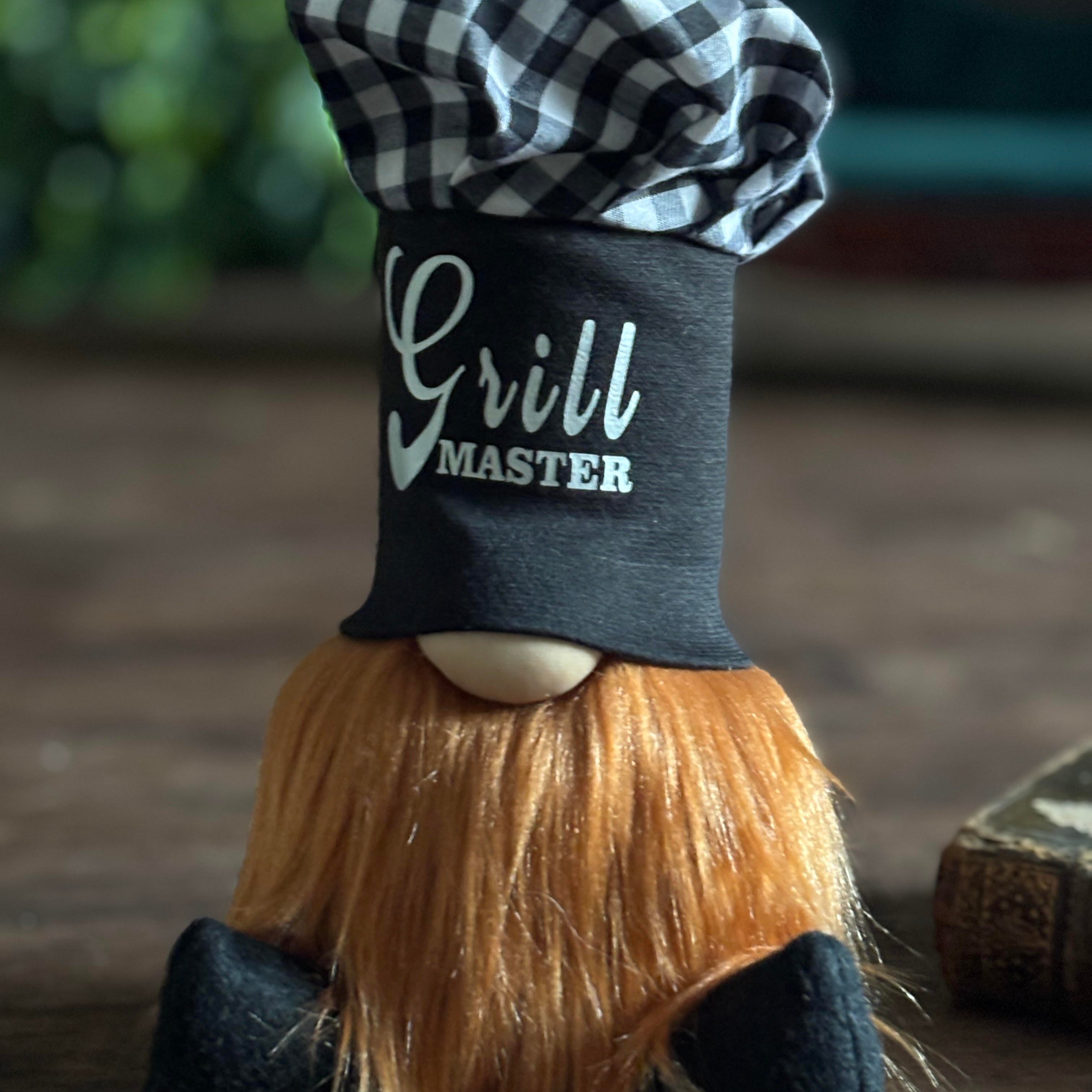 A gnome figurine with a long orange beard, Grill Master chef hat, and checkered top—Chef Gnocchi brings gourmet magic to your space.