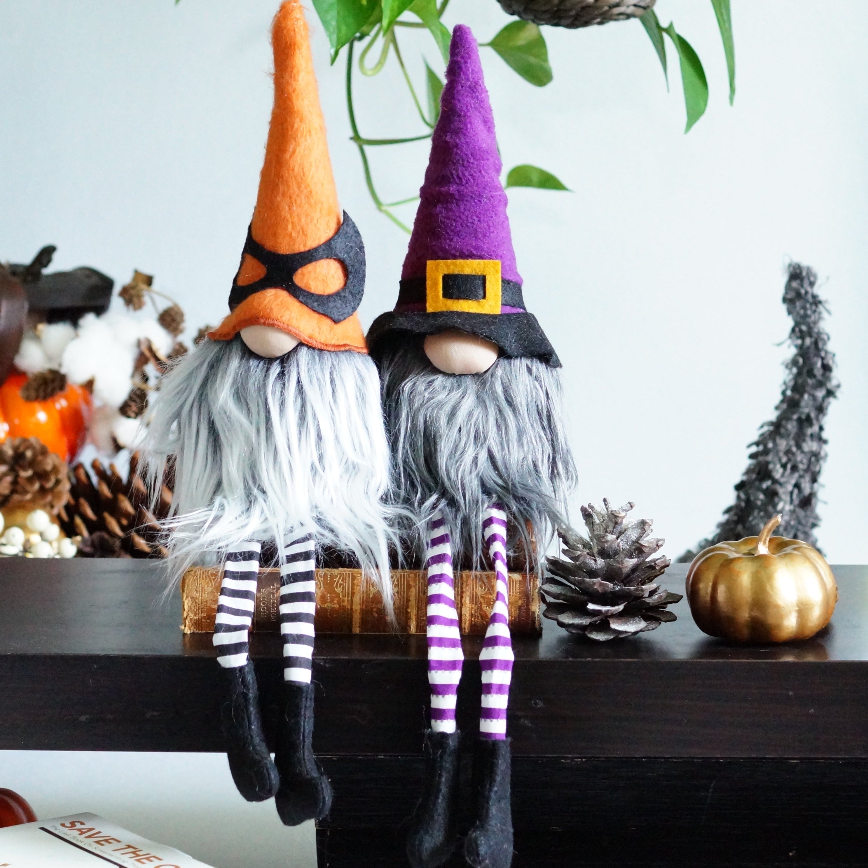 Two Halloween-themed gnomes on a table with pumpkins and decorations.