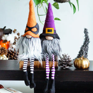 Two Halloween-themed gnomes on a table with pumpkins and decorations.