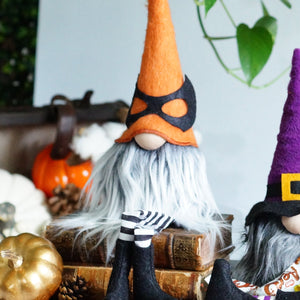 Two Halloween-themed gnomes on a table with pumpkins and decorations.