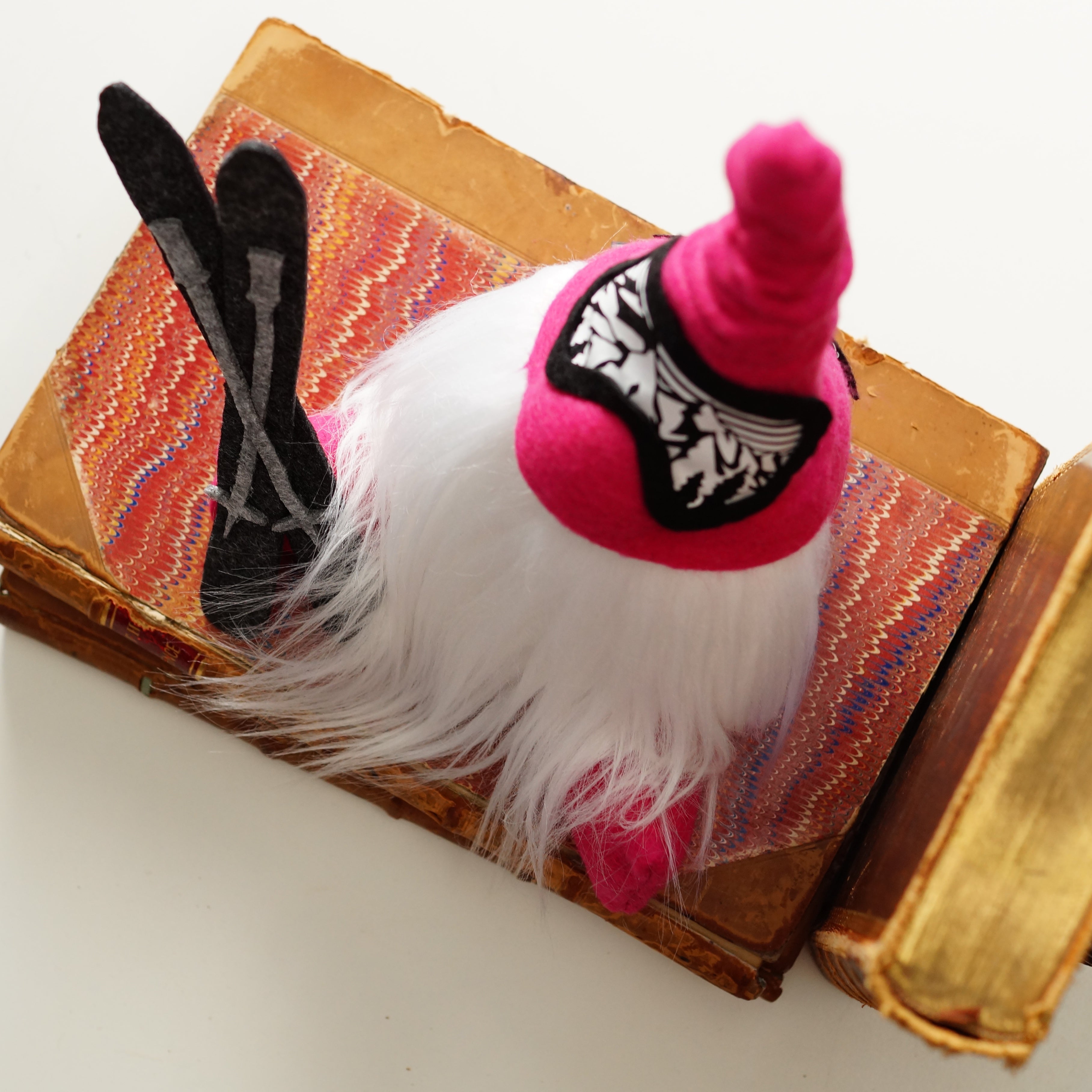 Small plush toy with a pink hat and white beard on an open book