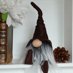 Load image into Gallery viewer, Gnome figurine with a white beard on a shelf with books and a pine cone.
