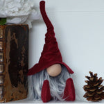 Load image into Gallery viewer, Gnome with a red hat and gray beard on a shelf with old books and a pine cone.
