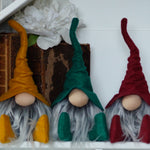 Load image into Gallery viewer, Three colorful gnomes with red, green, and yellow hats in a decorative setting.
