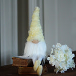 Load image into Gallery viewer, Gnome with a yellow hat and white beard sitting on a book next to a small bouquet of flowers on a wooden surface.
