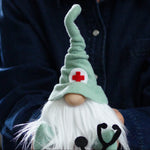 Load image into Gallery viewer, Doctor gnome held by a person in a  green gnome hat with a stethoscope and red cross symbol. Ideal graduation gift for the healthcare grad
