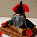 Load image into Gallery viewer, A Dracula Gnome with red collar and velvet cape  with a long gray beard, sits  books, surrounded by artificial red roses ideal for gothic tiered tray decor
