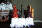 Load image into Gallery viewer, Four gnome figurines with different colored hats and white beards in front of a wooden chest and books.
