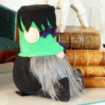 Load image into Gallery viewer, Gnome figurine with a green hat and gray beard on a surface with books and pumpkins in the background.
