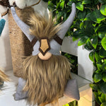Load image into Gallery viewer, A handmade Viking gnome with a horned helmet and brown beard sits on a shelf, serving as a charming focus guardian beside leafy plants.
