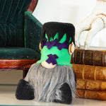 Load image into Gallery viewer, Halloween-themed gnome with green hair and purple X's on a table with books and pumpkins.
