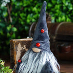 Load image into Gallery viewer, Decorative gnome with a long black hat and red ladybug buttons, sitting on a wooden surface with a blurred green background.
