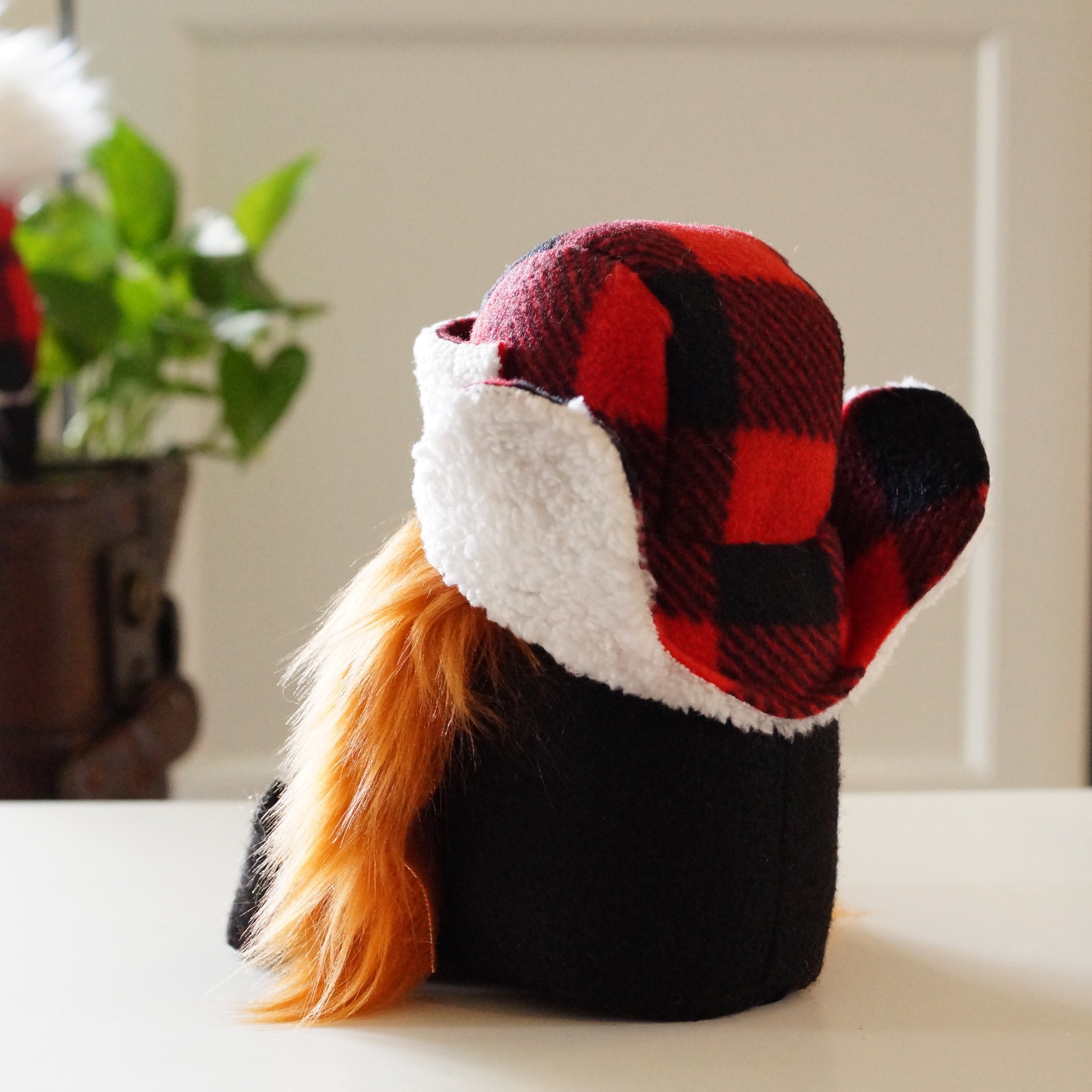 A gnome figurine with orange hair wears a red and black plaid winter hat, perfect as a charming cottage guardian for indoor or backyard protection.