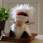 Load image into Gallery viewer, A plush gnome with a white beard, red and black hat, and faux fur trim sits on a book—a whimsical cottage guardian for your space.
