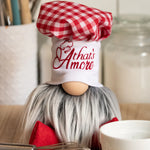 Load image into Gallery viewer, A handmade kitchen guardian, Papa Giuseppe, with a white beard and red checked hat sits on the counter near utensils and a candle.
