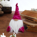 Load image into Gallery viewer, Small gnome figurine with a pink hat on a wooden surface with books in the background
