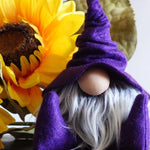 Load image into Gallery viewer, A handmade gnome with a long white beard and purple hat sits in front of a large yellow sunflower, perfect for your home office.
