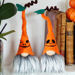 Load image into Gallery viewer, Two Halloween-themed gnomes with orange hats and black faces on a shelf with books and pumpkins.
