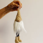 Load image into Gallery viewer, A hand holding a beige and white gnome ornament with long legs and boots.
