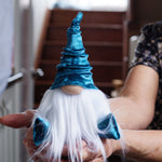 Load image into Gallery viewer, Person holding a gnome with blue hat and white beard in a kitchen setting
