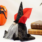 Load image into Gallery viewer, Dracula Gnome with a black hat, cape, and red collar in front of a pumpkin and books ideal for cute Halloween decorations
