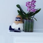 Load image into Gallery viewer, Gnome with a hat and striped socks next to a potted orchid on a white surface.
