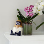 Load image into Gallery viewer, Decorative gnome with a hat next to potted orchids on a white surface.

