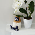 Load image into Gallery viewer, Small gnome figurine with a tan baseball cap with best dog mom across the cap sitting on a fireplace mantel under an orchid 
