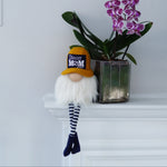 Load image into Gallery viewer, Gnome figurine with a gold hat and striped socks next to a potted orchid on a white surface. with best soccer mom write on the hat
