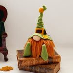 Load image into Gallery viewer, The Irish Lad, a handmade leprechaun gnome with a bendable green hat and a bright ginger beard, sitting on a stack of books. 
